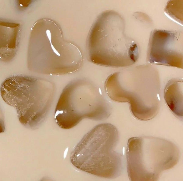 Heart-shaped ice cubes floating in creamy iced coffee close-up