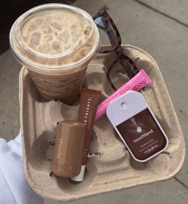Flat lay of Starbucks iced coffee, Rhode lip balm, and Touchland hand
sanitizer
